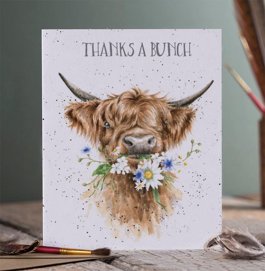 Thank someone with this card which features a lovely Highland cow with a mouth full of flowers and reads 'Thanks a Bunch.'