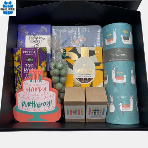 A birthday themed gift box that includes a birthday plaque, water bottle, birthday candles and chocolate in addition to other gourmet snacks.