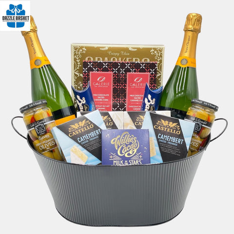 A Calgary gift basket with two bottles of Veuve Clicquot champagne and delicious snacks, cheese and chocolates arranged in a large metal container. A perfect gift delivery Calgary.