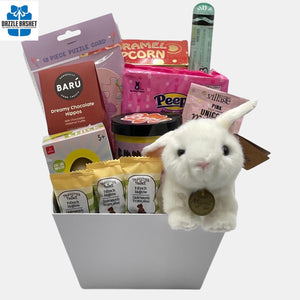A Calgary Easter gift basket containing Easter themed chocolates and gourmet snacks arranged creatively in a beautiful white market tray.