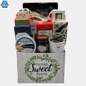A made in Calgary housewarming gift basket that includes gourmet sweet and savory snacks & household products to go with it. The products are arranged neatly in a "Home Sweet Home" container. 