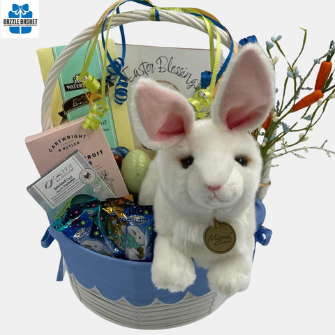 A Calgary Easter gift basket with large bunny plush toy and  themed chocolates and gourmet snacks arranged beautifully in a white basket with handle.
