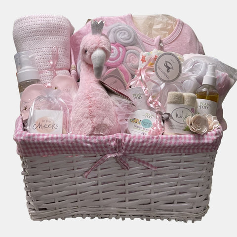 A baby girl gift basket that includes pink colored baby products including blanket, onesie, shoes and a beautiful Flamingo packed in a lovely white basket.