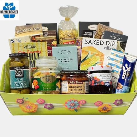 A family gourmet gift basket made in a large green tray and includes several gourmet products including pasta, candies, chocolates, snacks, jams arranged beautifully in the bright grren tray.