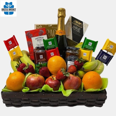A made in Calgary champagne & fruit gift basket that includes fresh fruits, a bottle of Veuve Cliquot champagne, chocolates, crackers, cheese, jams and shortbread cookies arranged neatly in a rectangular basket.