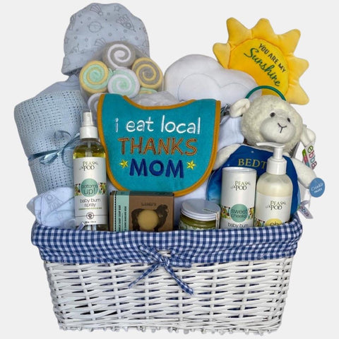 A baby boy gift basket that includes quality baby products including blanket, onesie, shoes and a beautiful "You are my Sunshine" plush toy packed in a lovely white basket. with blue liner.