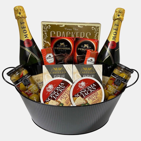 A Calgary gift basket with two bottles of Moet champagne and delicious snacks, cheese and chocolates arranged in a large metal container. A perfect gift delivery Calgary.