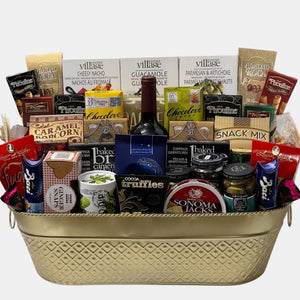 A gigantic Calgary gift basket with a bottle of wine, quality gourmet snacks and a plush reindeer toy arranged in an innovative manner in an extra large metal basket.