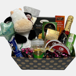 A made in Calgary gourmet gift basket with a bottle of Champagne and "Happy Cow" plush toy with a Congrats banner.